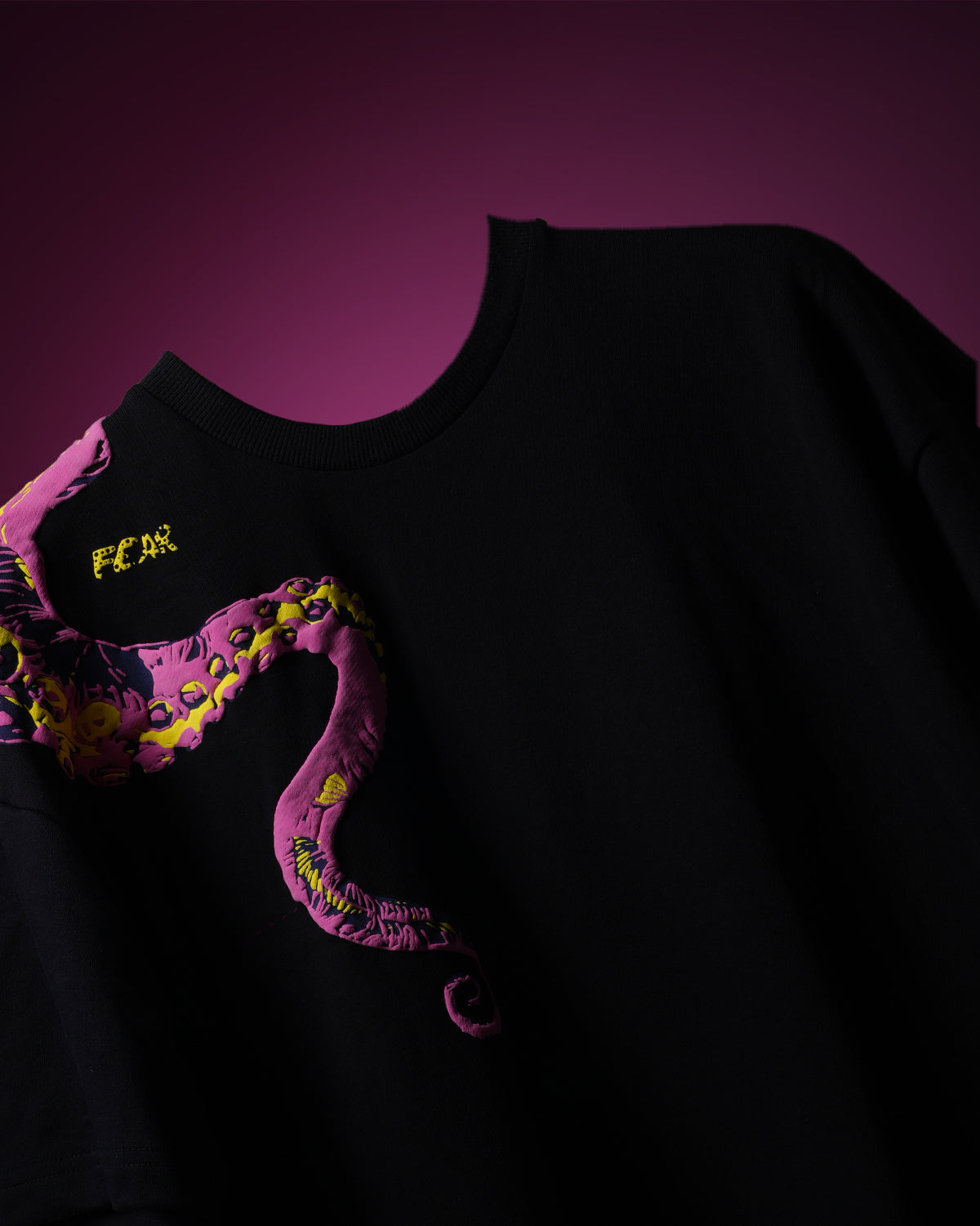 Black t-shirt with colorful graphic design on a pink background