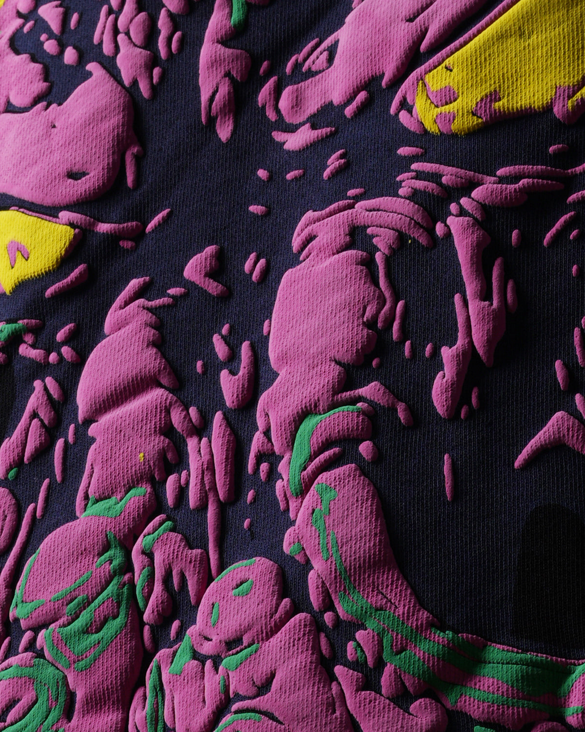 Close-up of a textured fabric with pink and green patterns on a dark blue background