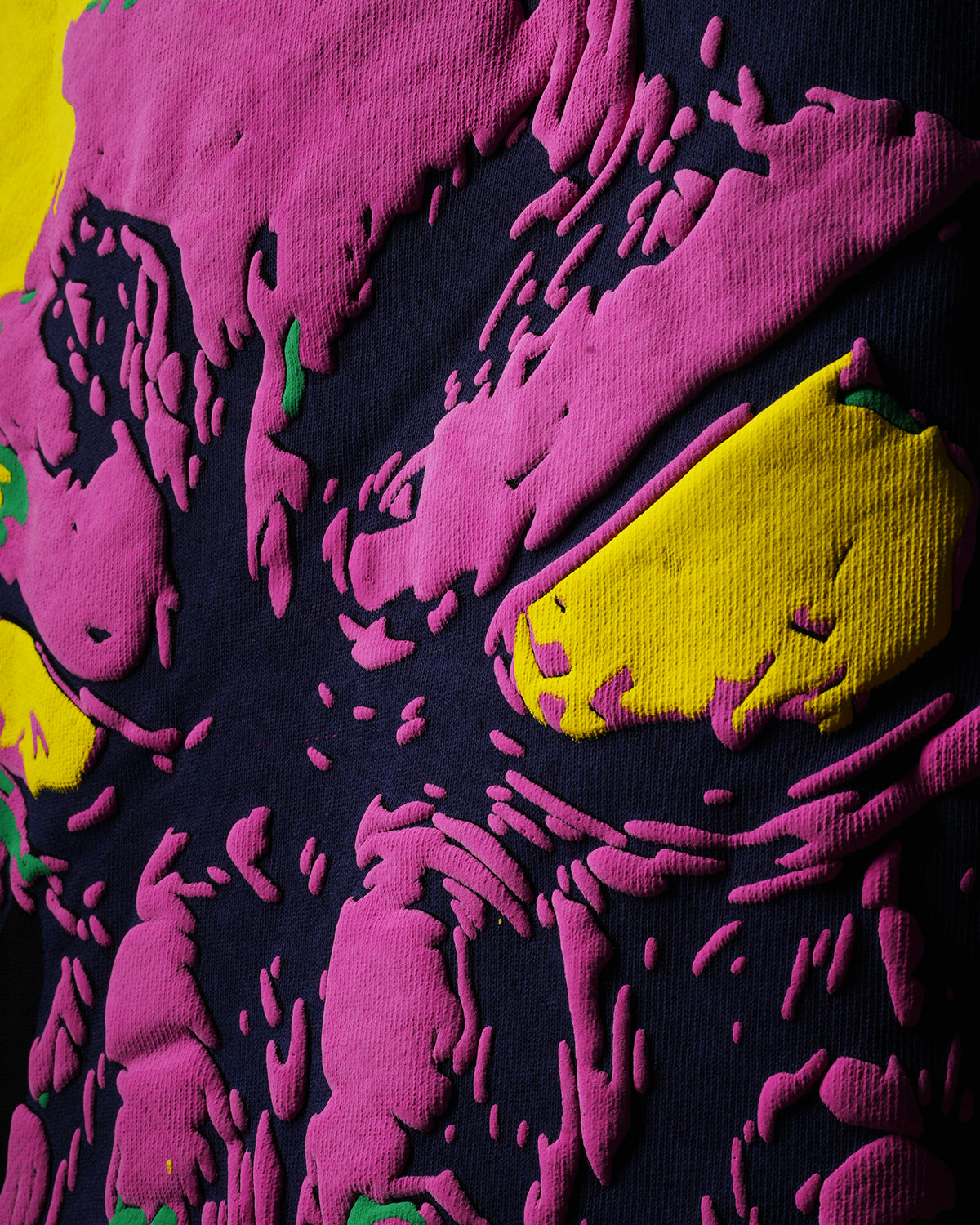 Close-up of a textured fabric with pink and yellow puff on a dark background